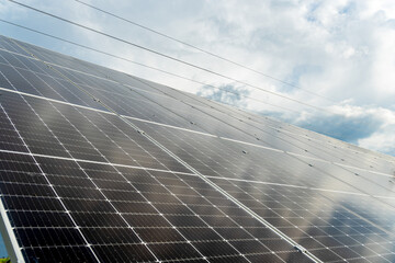 Solar panels reflecting cloudy sky. Renewable green energy generation technology outdoors.