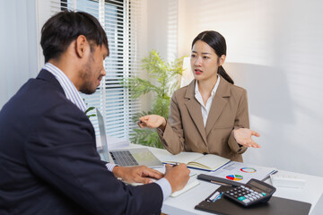 Business colleagues are engaged in a collaborative discussion, analyzing financial charts and reports on the wall and table. They exchange ideas, review strategies, and plan future goals.