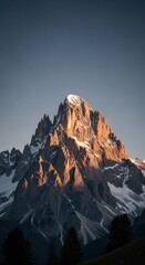 Majestic mountain peak glowing at sunset with snowy slopes