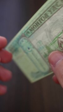 Vertical macro shot of man's hands and Mongolian Tugrik (MNT) banknotes. Concept of saving money for retirement, cash settlement, financial success, literacy and income planning in Mongolia.