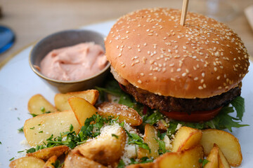 Juicy burger with fries and sauce on a plate
