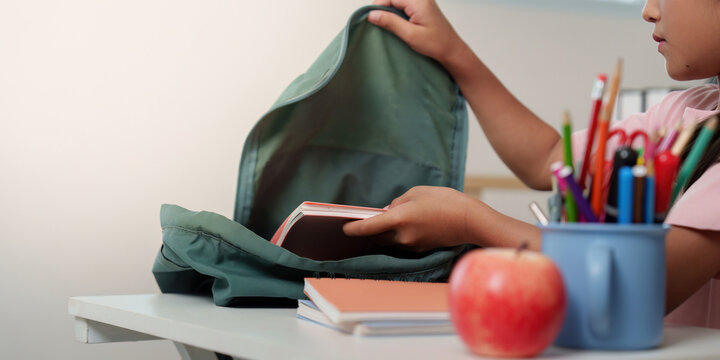 Back to School. Child organizing school supplies in backpack.