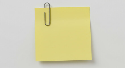 Bright yellow sticky note secured with a silver paperclip on a clean surface