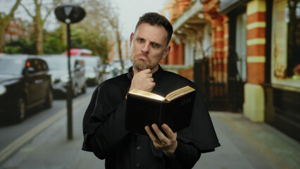 Priest reading book on urban street with thoughtful expression under cloudy sky as cars pass by during daytime