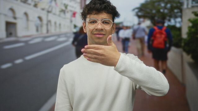 Man covers eyes with hand while standing among blurred pedestrians on busy city street; embarrassment.