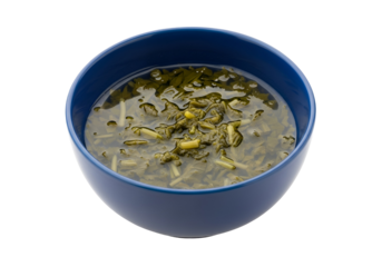 A deep blue bowl brimming with a vibrant green soup, showcasing delicate soup elements against a stark black background.