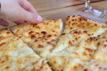 Cheesy Garlic Flatbread with Hand Reaching for Slice