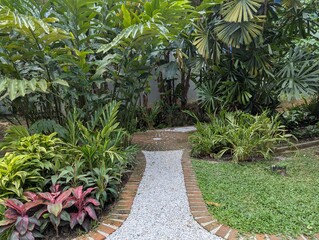 Tropical garden with colorful plants (cordyline, shell ginger and stone and brick pathway
