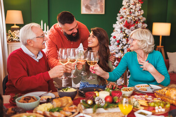 Couple making a toast with senior parents while having family Christmas dinner at home