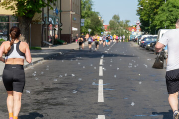 Numerous used plastic cups discarded on the asphalt after a city marathon
