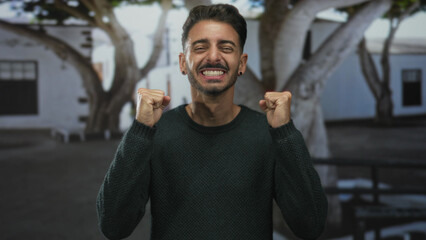Man wearing green sweater with thumbs pointing to chest on street; surprise doubt confusion identity.