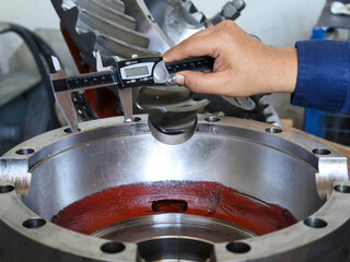 Close-up shot of a person's hand using a digital caliper to measure the inside diameter of a large,...