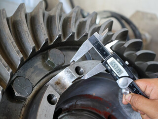 Close-up shot of a person's hand using a digital caliper to measure the dimensions of a large...