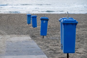 Row of blue trash cans keeping the beach clean