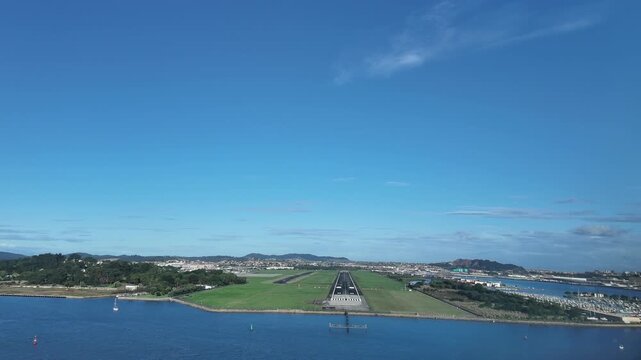 An immersive pilot&rsquo;s view from the cockpit of a jet in the final approach for landing at coastal Santander Airport runway in a quiet sunny morning under a blue sky.