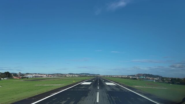 An immersive pilot&rsquo;s eye view FPV in a real time landing at Santander airport runway, surroended by green fileds , under a bright, unclouded blue sky.