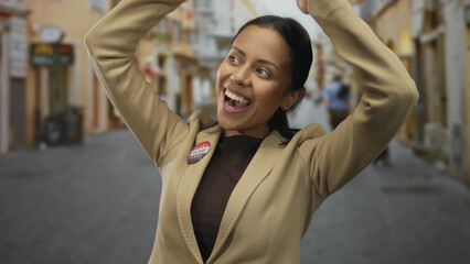 Young hispanic woman outdoors streets of united states wearing badge with flag smiling after voting...