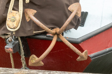 Grapnel anchor resting on red and white boat hull
