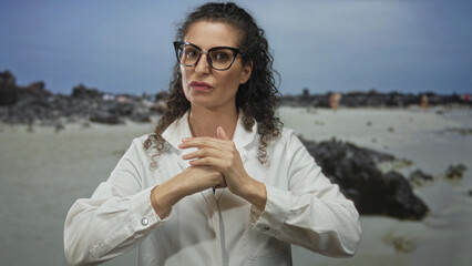 Woman hits her palm with a clenched fist on a sandy beach in a fight gesture showing bare hands; determination.