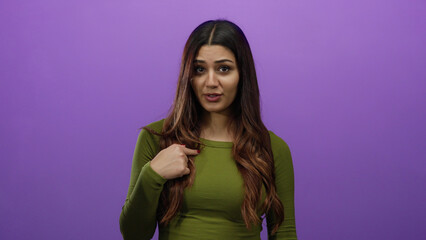 Woman pointing and shaking finger on purple background expressing disagreement or denial with hispanic features in a studio setting.