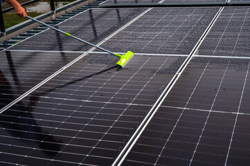 Solar worker using mob cleaning dirt on solar panels surface on roof