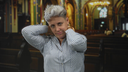 Woman raising arms and tilting head forward with eyes closed inside church building; serenity calm reflection.