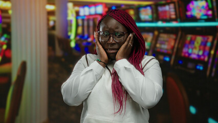 Woman in casino looking anxious near slot machines surrounded by vibrant lights and intense atmosphere capturing the high stakes environment.
