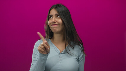 Young hispanic woman pointing her index finger with a dismissive gesture in an isolated pink studio...