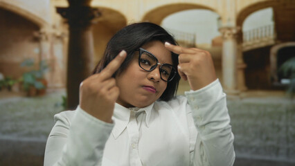 Young woman at an old university courtyard displaying a defiant expression in outdoor setting, capturing the essence of cultural heritage and modern attitude.