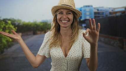 Woman with visible cleavage and open palm presentation gesture on street wearing sunhat and polka...