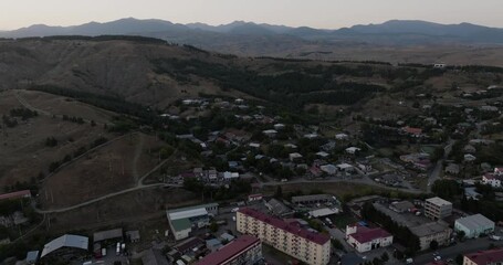 Aerial view of buildings nestled near mountains, a blend of urban and natural landscapes under a soft sky, Akhaltsikhe, Samtskhe-Javakheti, Georgia.