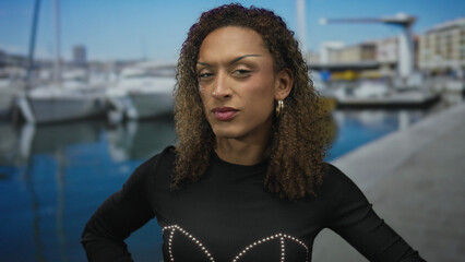 Transgender woman cups hand to ear beside a docked boat at a sunny port with calm water reflecting...