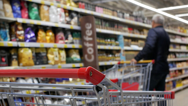 A male customer with a shopping trolley choosing coffee in a coffee department