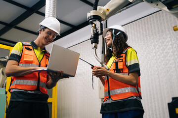 Engineer students in safety gear learning AI and robotics in modern lab, collaborating with industrial robot and laptop, concept of STEM education, teamwork, and future technology.