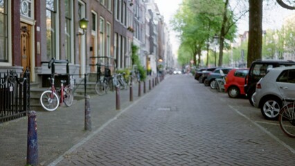 Blurred urban street scene in amsterdam with bicycles, trees, and parked cars creating a defocused cityscape capturing the essence of the netherlands.