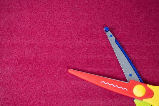 Open colorful craft scissors with zigzag blade on pink background
