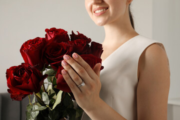 Dreams come true. Happy woman with engagement ring and beautiful bouquet indoors, closeup