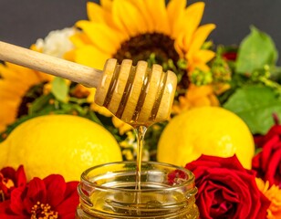 Honey drizzled from wooden dipper over lemons and sunflowers