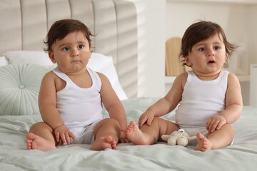 Cute little twin babies on bed at home