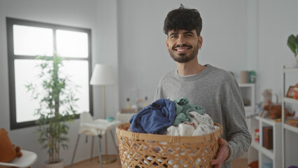 Young man holding basket of laundry in bright indoor children room with natural light and decor.