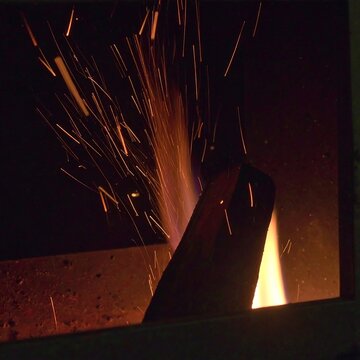 Sparks flying from a metal object in a dark firebox