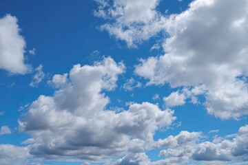 Naklejka premium Fluffy white clouds fill a bright blue sky creating a serene and airy atmosphere