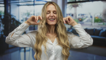 Woman ears covering hotel lobby scene shows young blonde indoors frustrated expression.