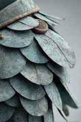Obraz premium Close-up of a textured, leaf-like armor piece, muted teal color, with a circular button