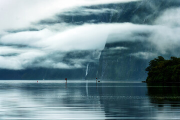 Mysterious landscape of Milford Sound or Rahotu with waterfall in foggy on the lake at Fiordland national park, New Zealand