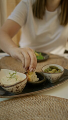 Woman enjoying mediterranean appetizers indoors at a restaurant showcasing rich food textures and casual dining atmosphere.