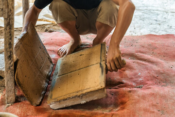 Manual clay tile making with worker shaping, drying and organizing terracotta in traditional workshop showing heritage craft and raw material process