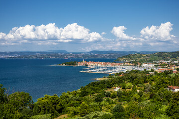 Fototapeta premium panoramic view of coastal town and forested hills. coastal town with marina, vibrant greenery by the deep blue see. old