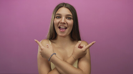 Teenage girl wearing yellow tank top and bracelets pointing fingers across bare shoulders in...