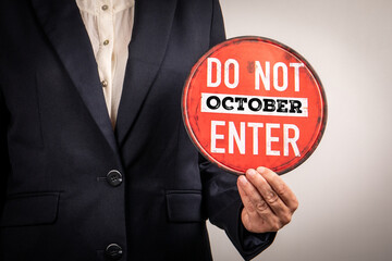 Close-up of a person in formal suit holding a round red warning sign that reads Do Not Enter...